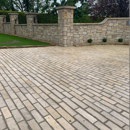 Driveway paved using Mountcharles Sandstone Paving Setts in Random Length x 100mm. Stone boundary wall and grass in the background. 