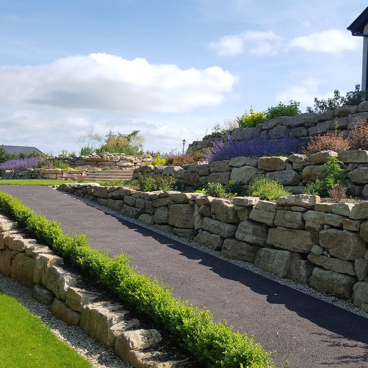 Tiered Stone wall completed using Mountcharles Sandstone Rockery with garden and pathway in a residential area