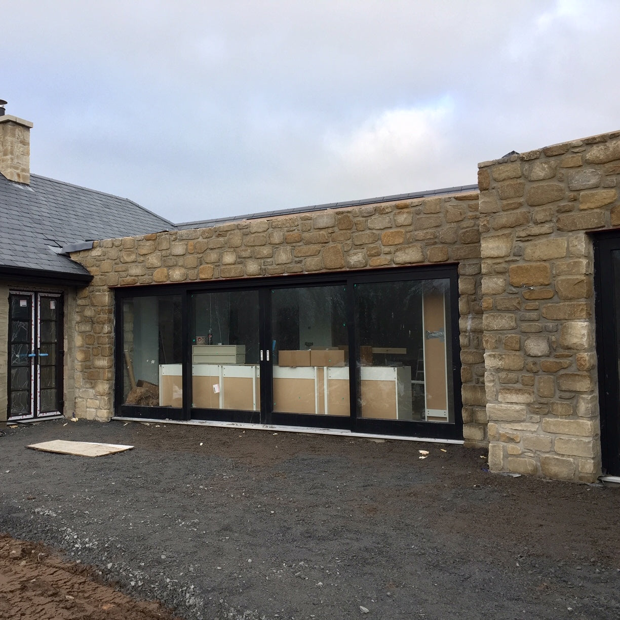 New home construction with stone façade in Mountcharles Sandstone Tumbled and large glass door.