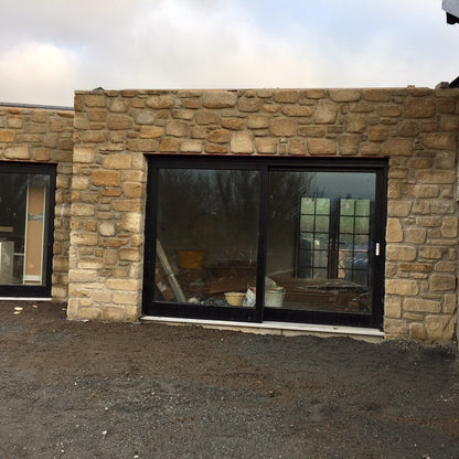 Stone wall in Mountcharles Sandstone tumbled stone with large glass doors. 