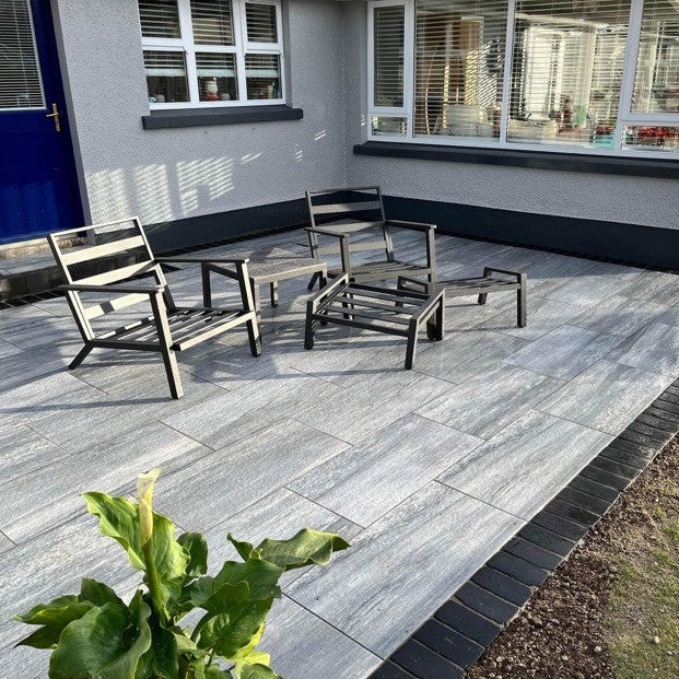 House with blue door looking out onto porcelain patio featuring Black Limestone Cobbles in 200 x 100mm size. 