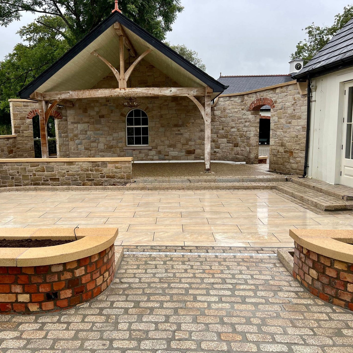 Rustic patio area with natural stone walls in the background. Paving is Pietra Di Barge porcelain tiles.