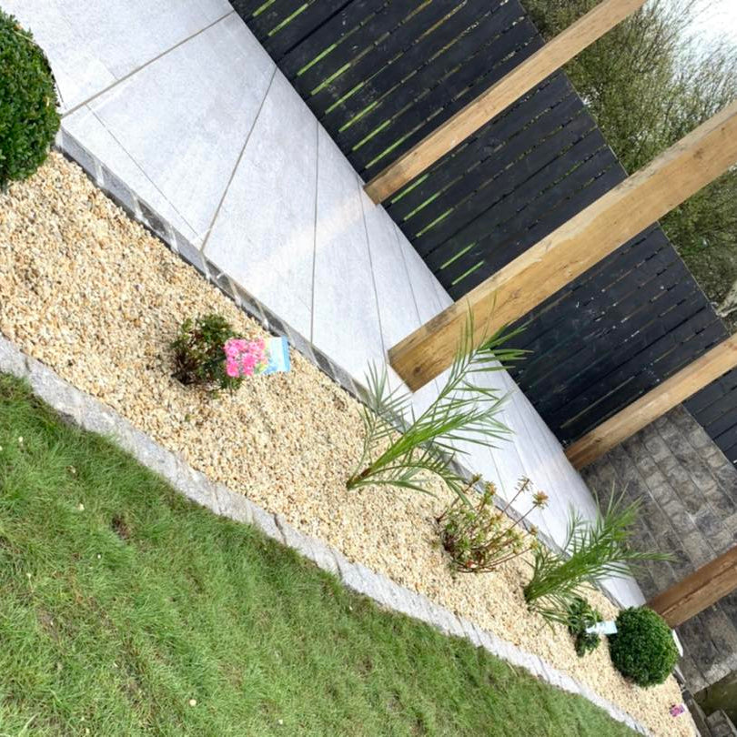 Patio featuring Pietra di Bagnolo porcelain tiles surround by fence and planting.