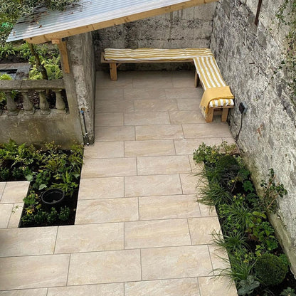 Patio design featuring Pietra Di Barge porcelain tiles. L shape bench with mustard striped seating cushion in the background. 