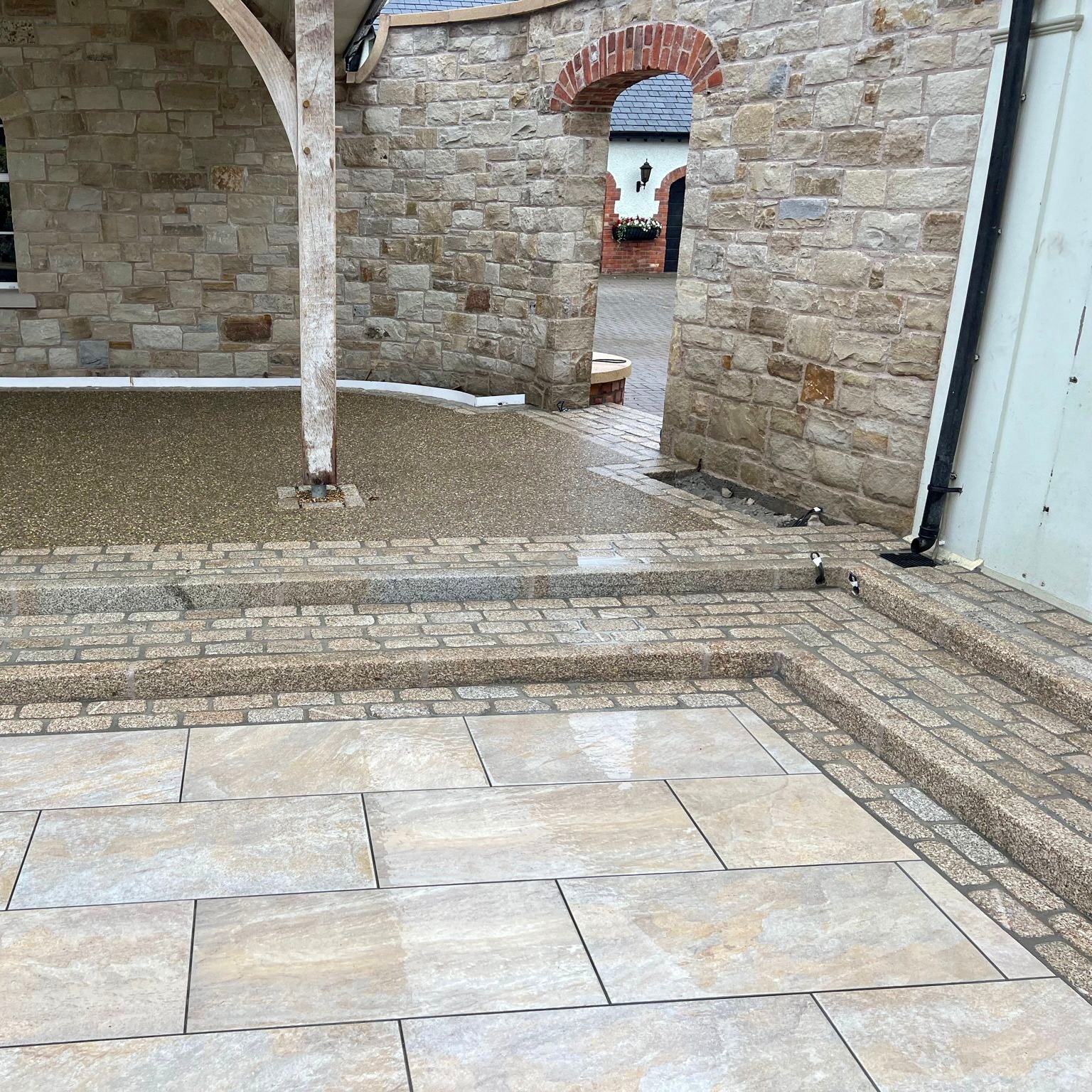 Close up of patio area featuring Pietra Di Barge porcelain tiles and natural stone walls in the background. 