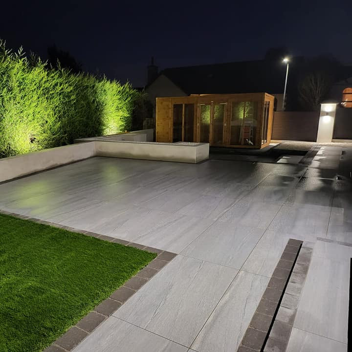 Same large patio with shed in the background photographed at night. Paving is Pietra di Vals porcelain tiles