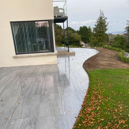 Pietra Di Vals Porcelain Paving Tiles installed on a curved patio area outside a modern hose with balcony.