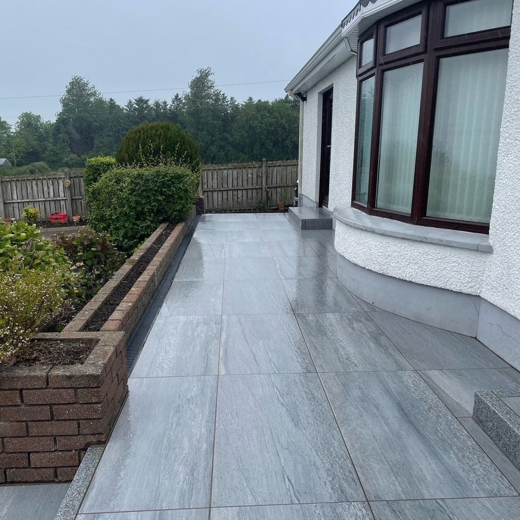 Pathway completed in Pietra Di Vals porcelain paving with a low wall alongside with mature planting. 