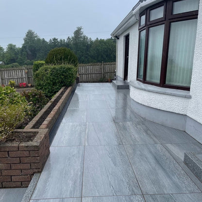 Pathway completed in Pietra Di Vals porcelain paving with a low wall alongside with mature planting. 
