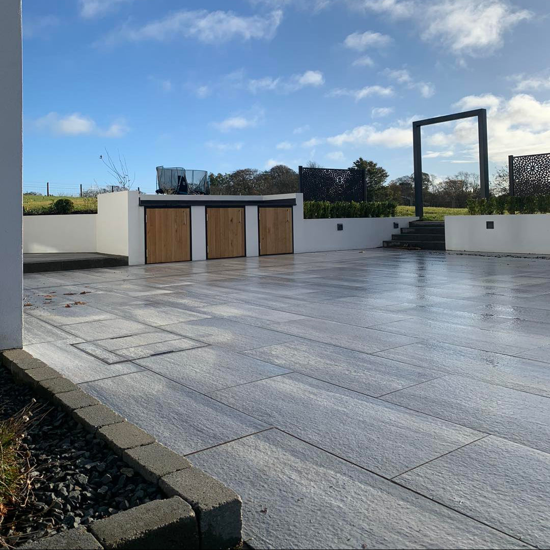 Large patio area completed using Pietra di Vals porcelain tiles. White wall in background. 