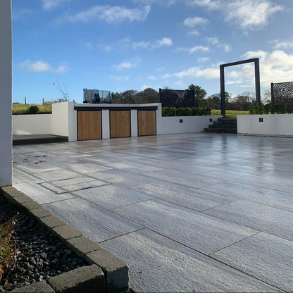 Large patio area completed using Pietra di Vals porcelain tiles. White wall in background. 