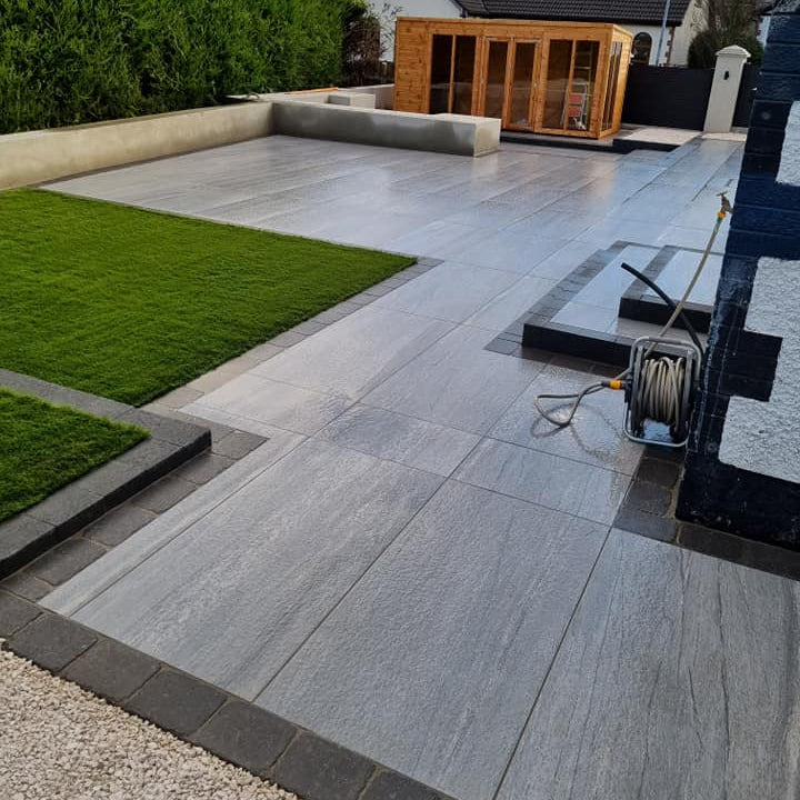 Large patio area featuring Pietra Di Vals Porcelain Tiles. Wooden Outdoor room in the background. 