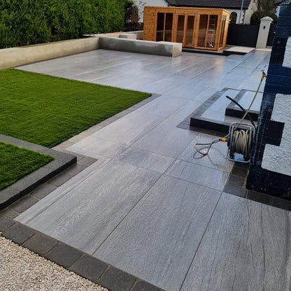 Large patio area featuring Pietra Di Vals Porcelain Tiles. Wooden Outdoor room in the background. 