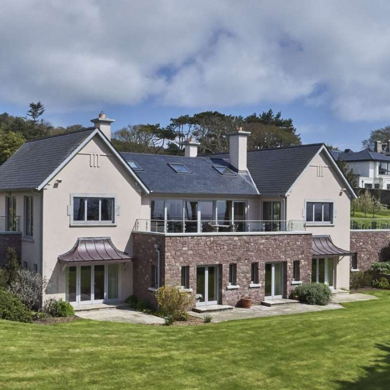 Large modern house with natural stone feature wall in Pink Sandstone Machined building stone. 