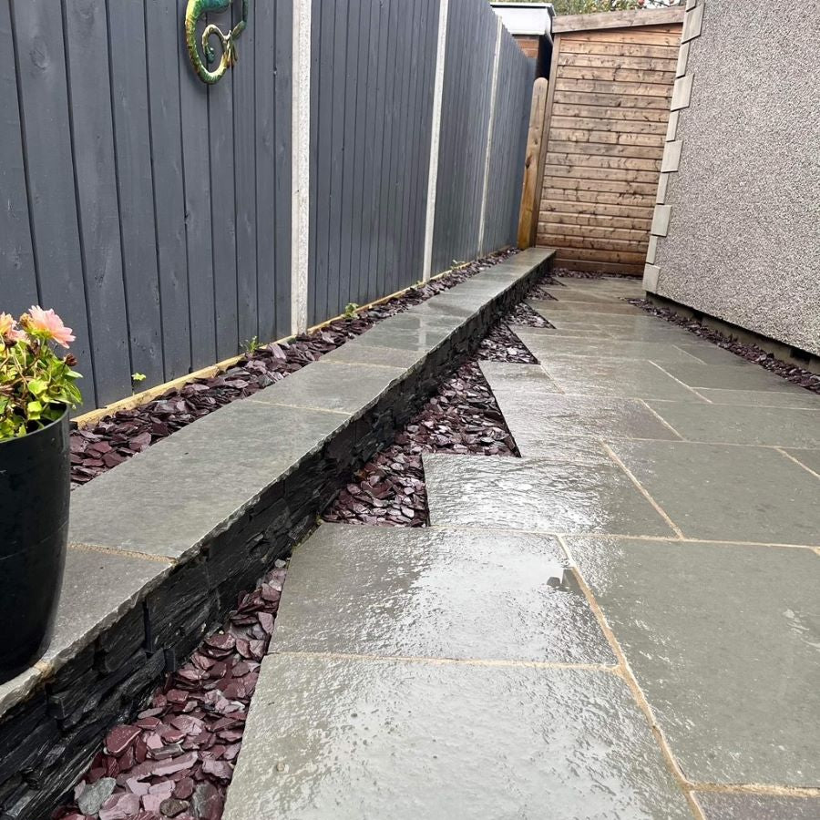 Paved pathway with decorative stones on the side, leading to a building. Stones are Plum Slate Mulch. 