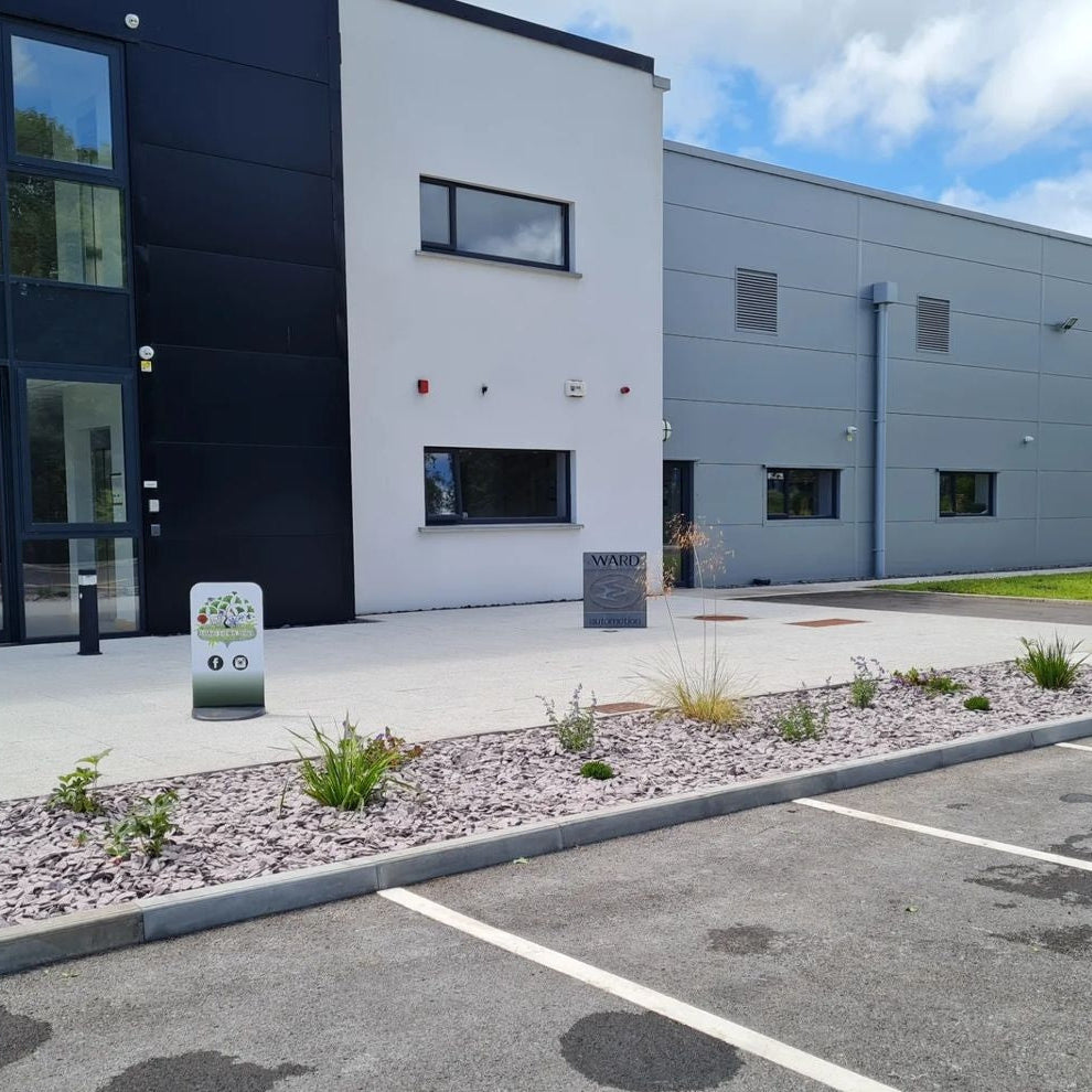 Modern building exterior with a small garden area and parking lot.