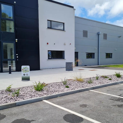 Modern building exterior with a small garden area and parking lot.