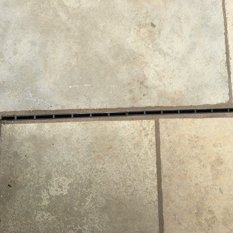 Poly Brick Slot Channel Drain installed in a natural stone patio. 
