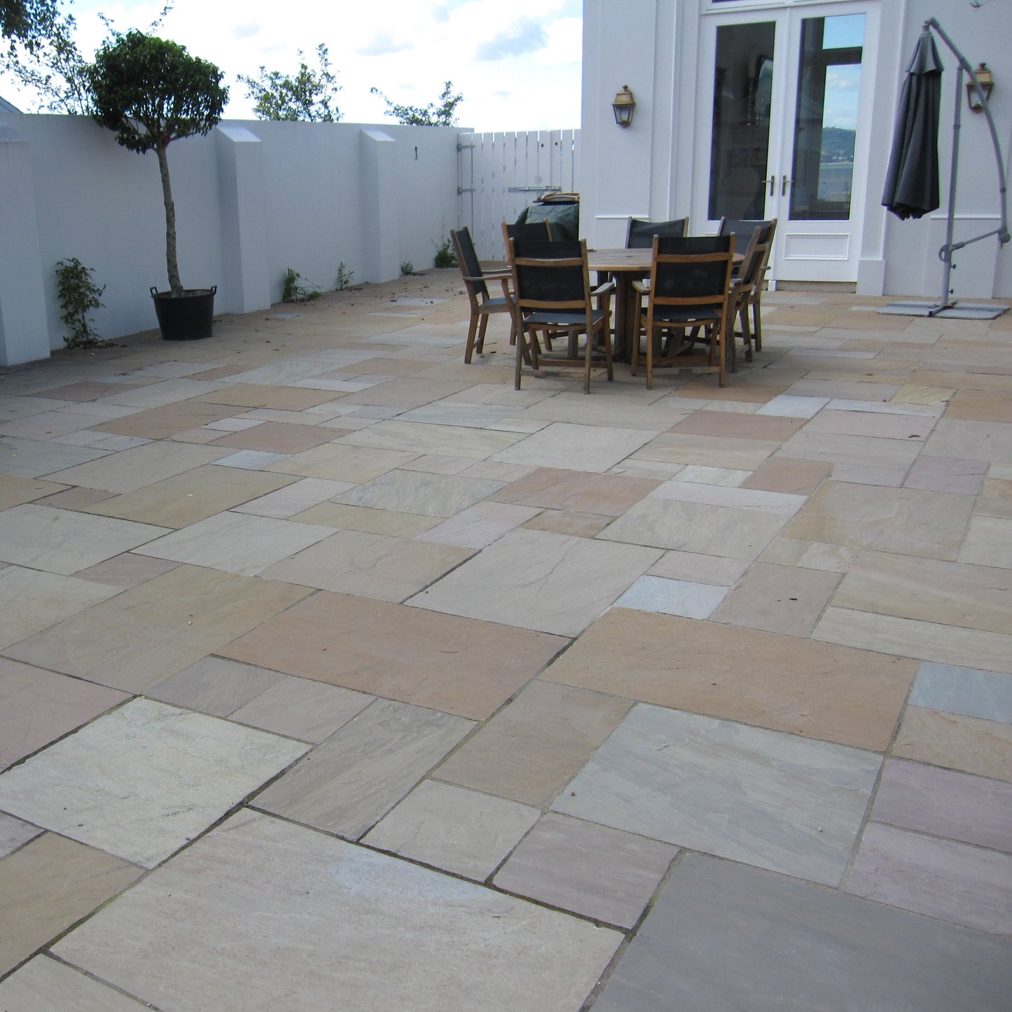 Patio area featuring Raj Green Sandstone Paving with outdoor furniture and plants. 