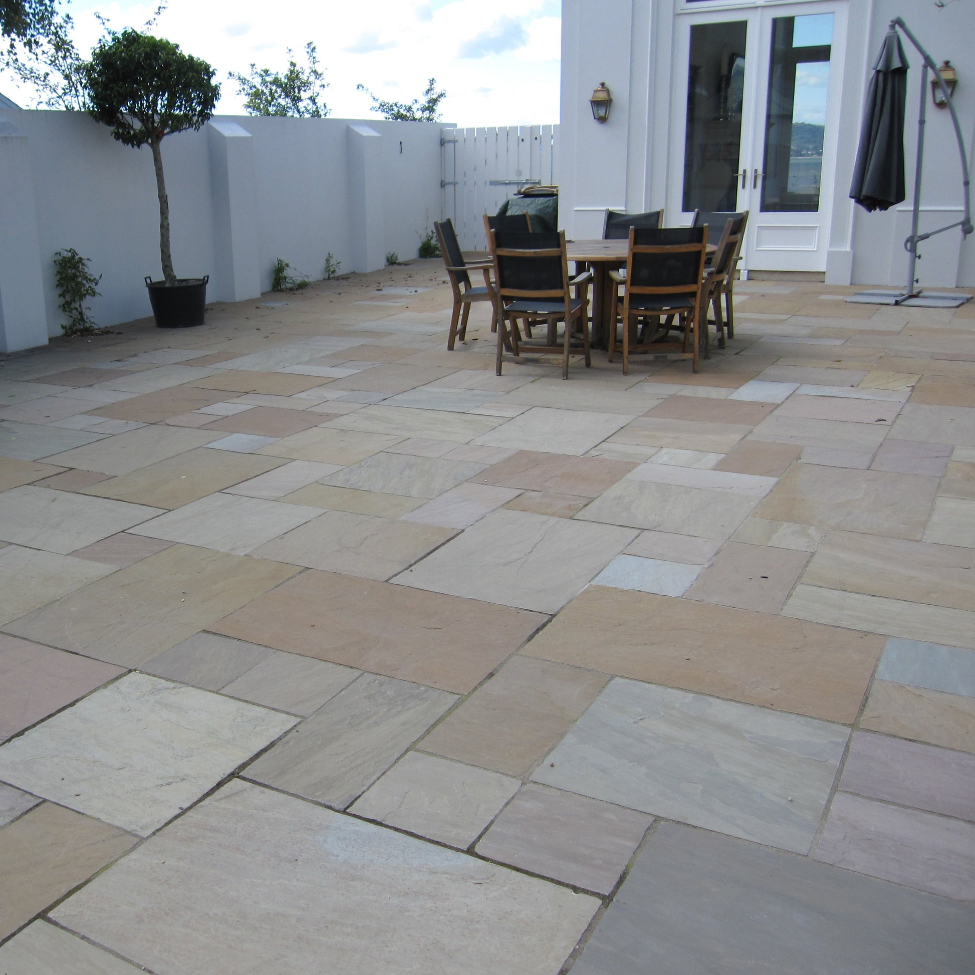 Patio area featuring Raj Green Sandstone Paving with outdoor furniture and plants. 