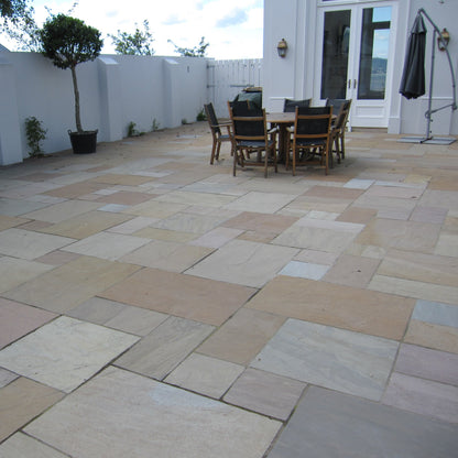Patio area featuring Raj Green Sandstone Paving with outdoor furniture and plants. 