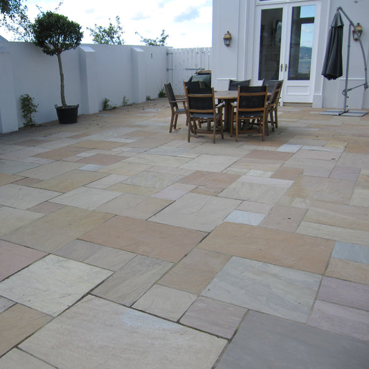 Patio area featuring Raj Green Sandstone Paving with outdoor furniture and plants. 