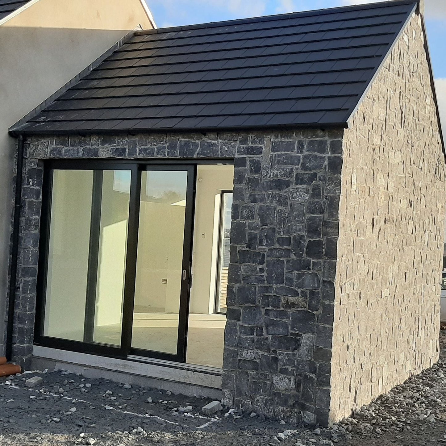 Modern house exterior with stone facade in Rustic Blue Limestone and glass door, cloudy sky