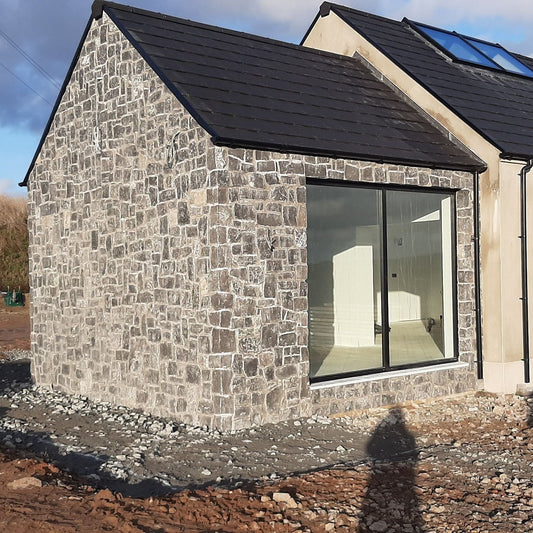 New build under construction with stone façade featuring Rustic Blue Limestone Stoneer Cladding. 