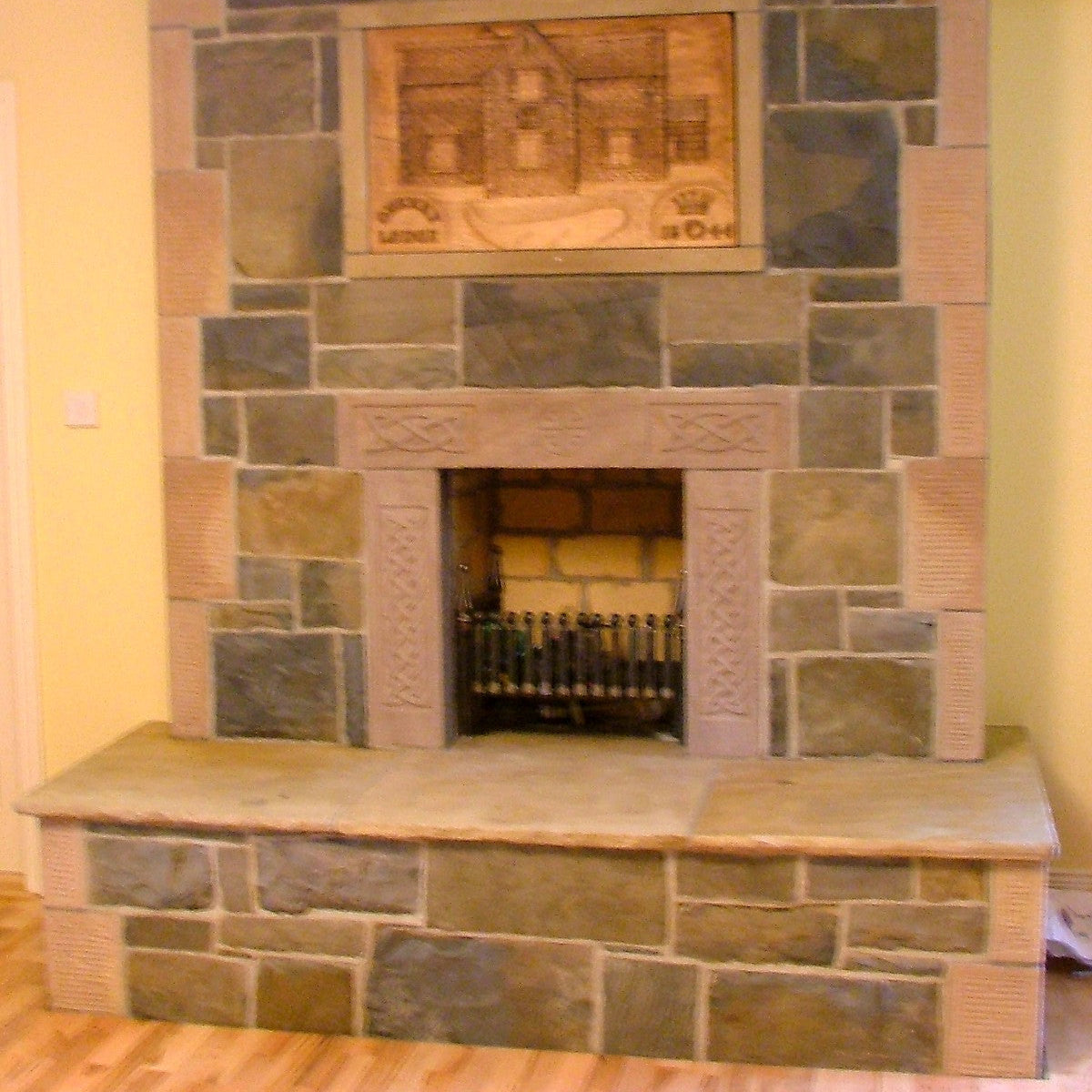 A traditional fireplace featuring an unique Sandstone Fireplace Surround with celtic design detail. 