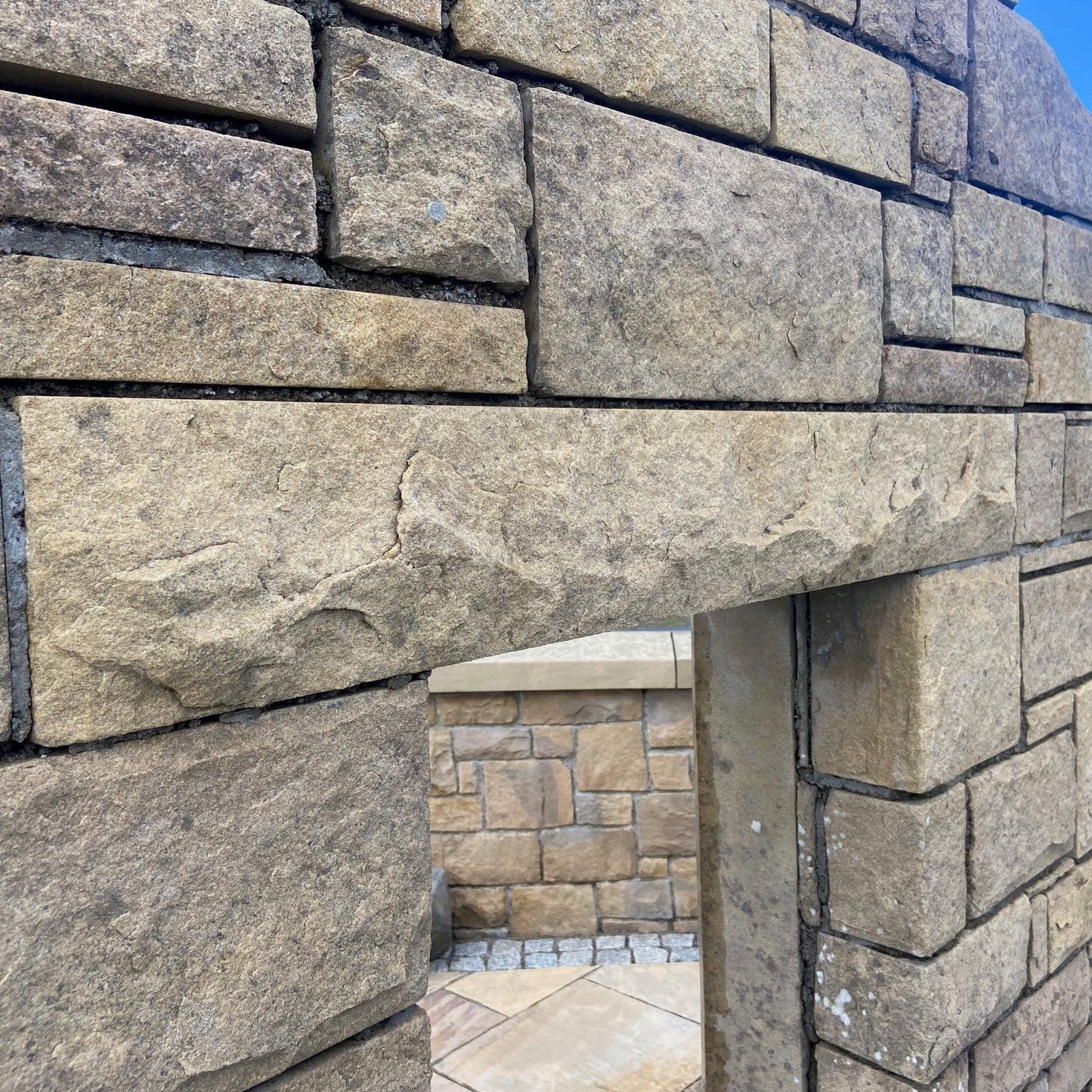 Stone display wall with bespoke sandstone lintel with a rockfaced finish. 