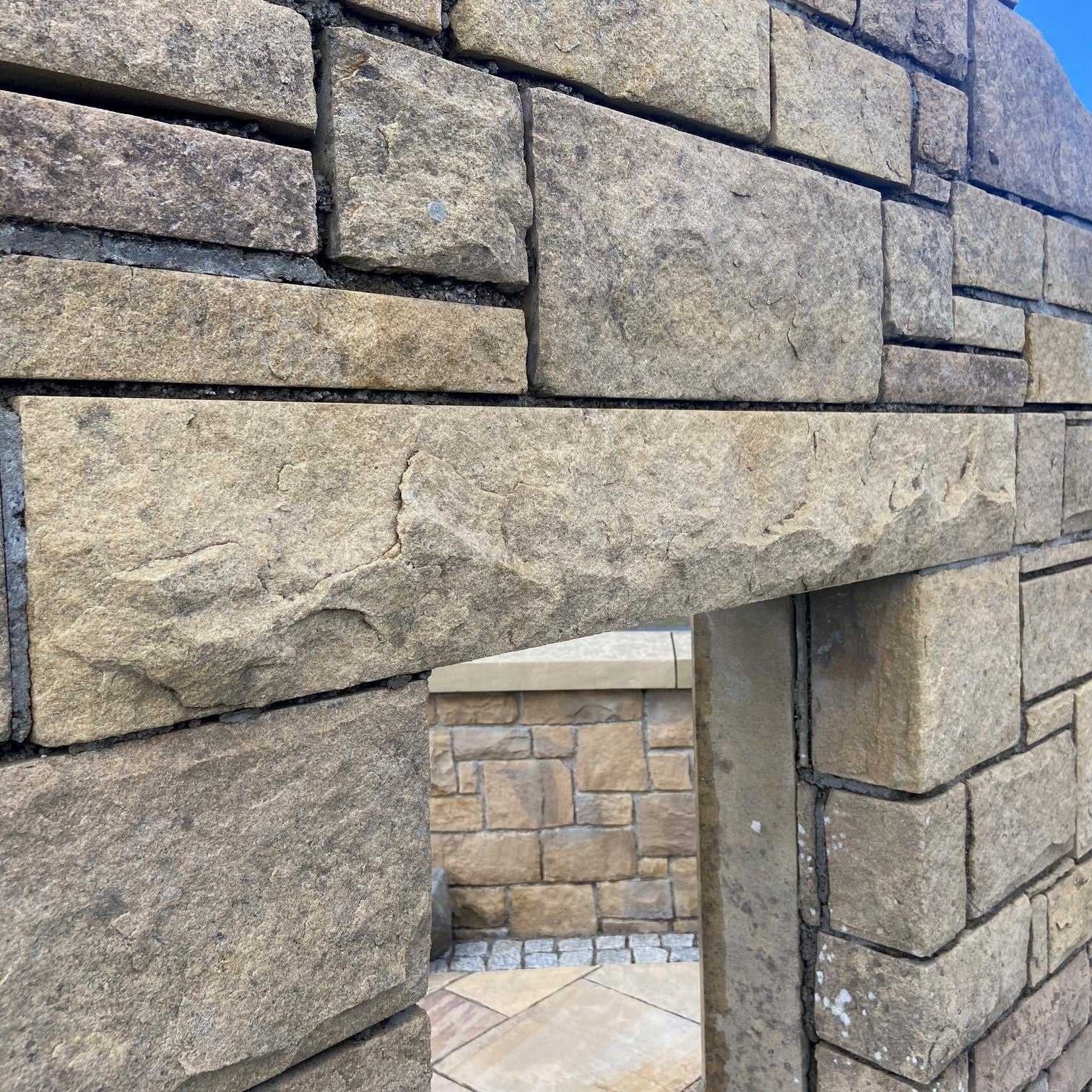 Stone display wall with bespoke sandstone lintel with a rockfaced finish. 