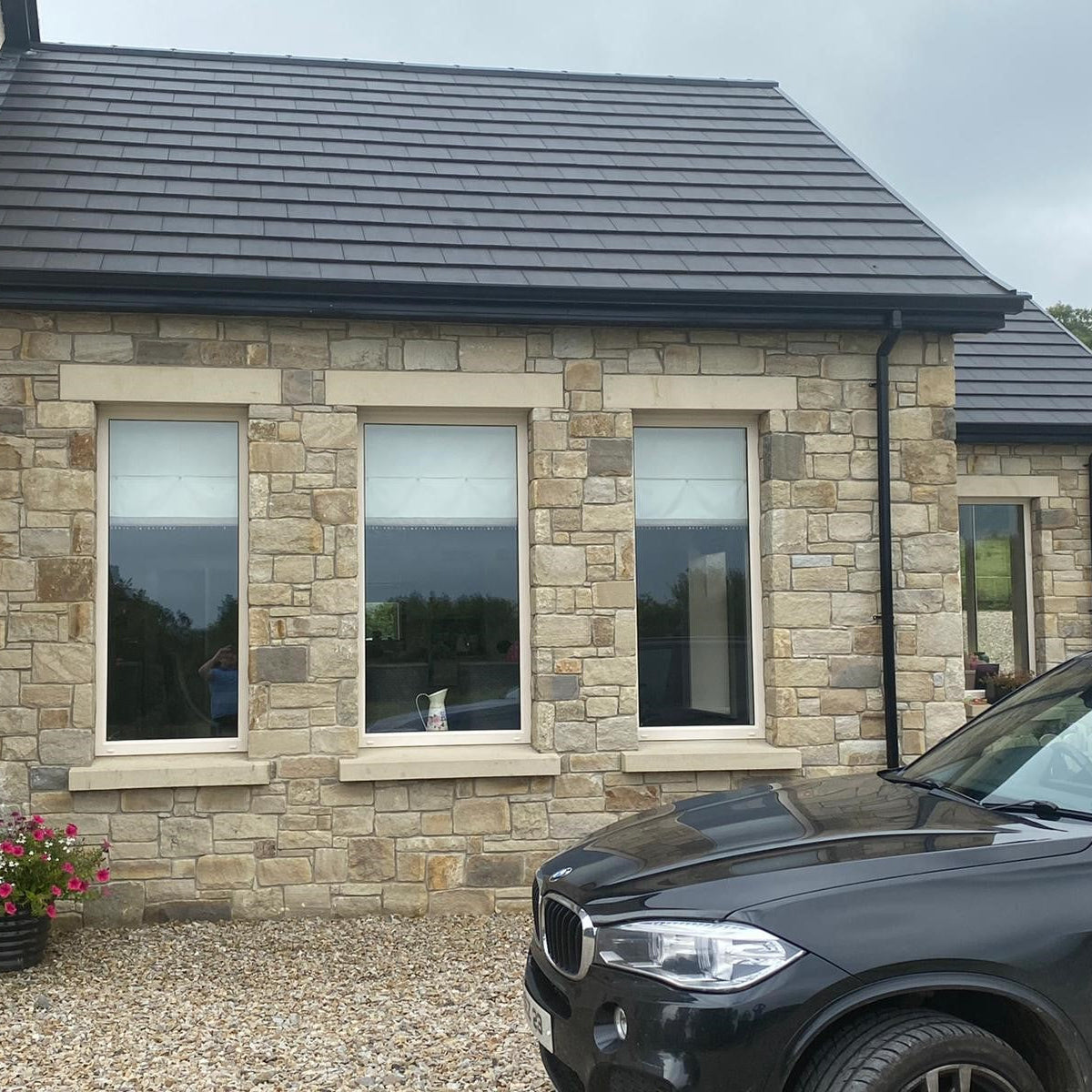 Modern house exterior with a black car parked in front. Windows feature Sandstone Lintels and Sills. 