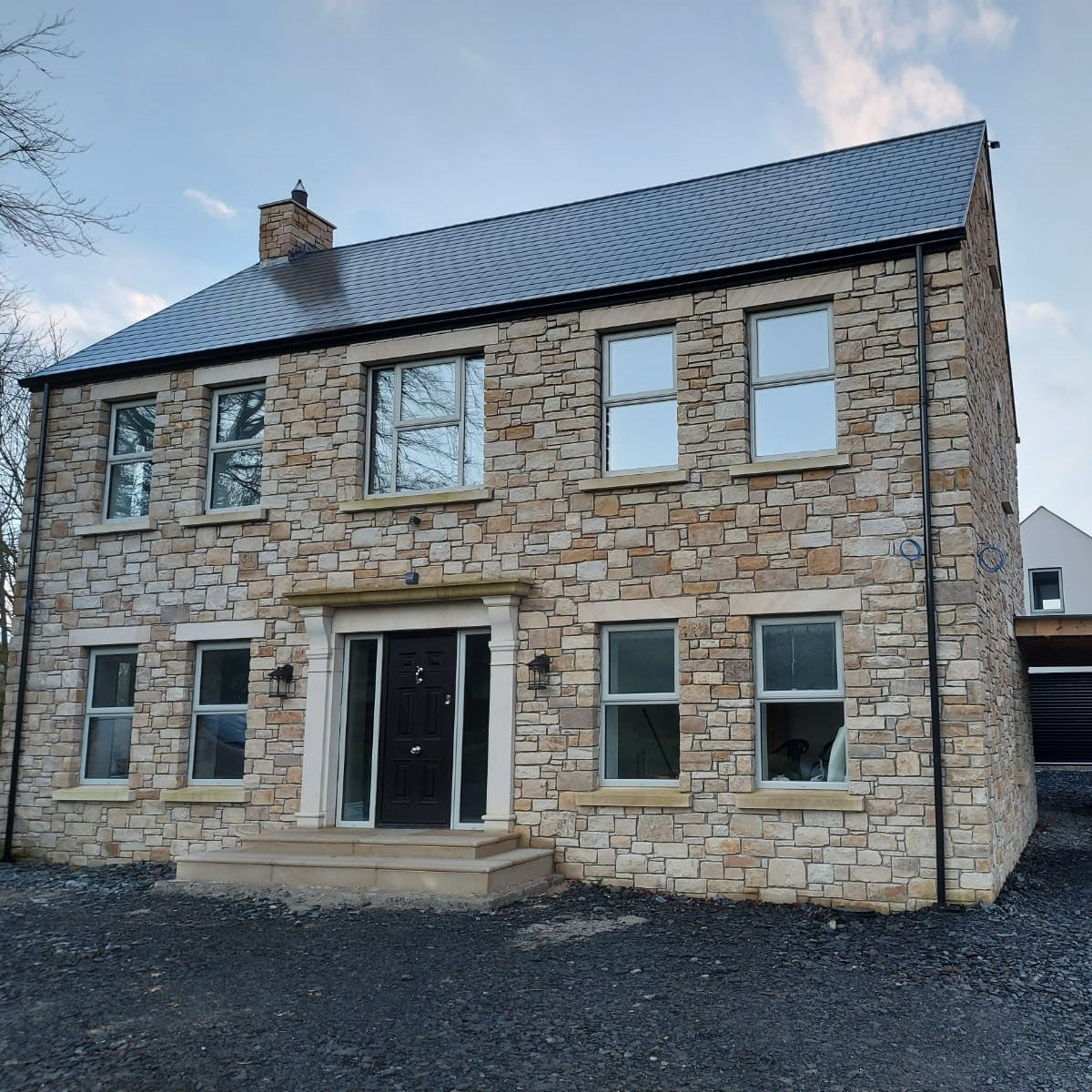 Two-story stone house with Bespoke Sandstone Lintels above windows and door. 