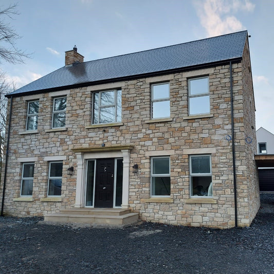 Two-story stone house with Bespoke Sandstone Lintels above windows and door. 