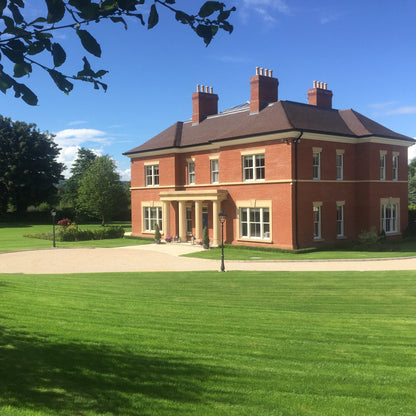 Large two storey red brick house with a sandstone portico and sandstone window surrounds and lintels. 