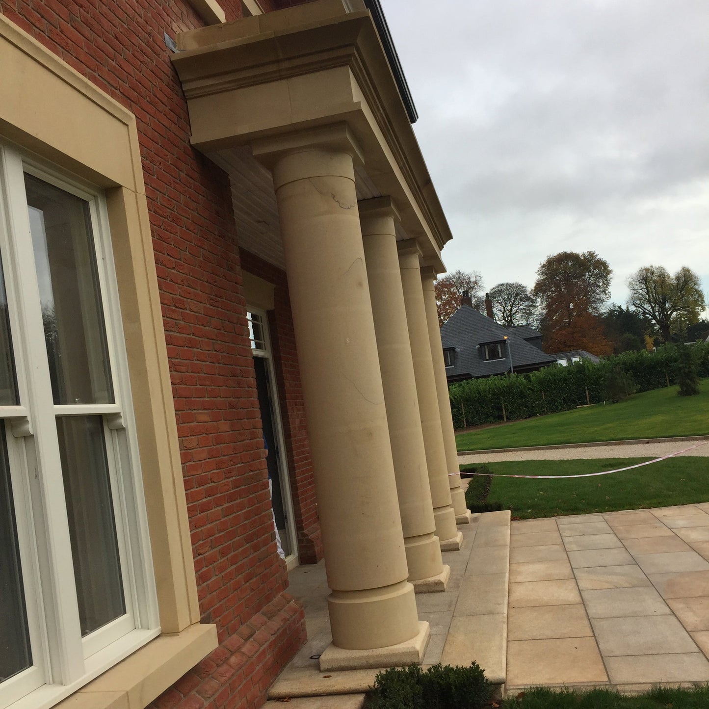 Brick building with decorative sandstone columns and a lawn in the background
