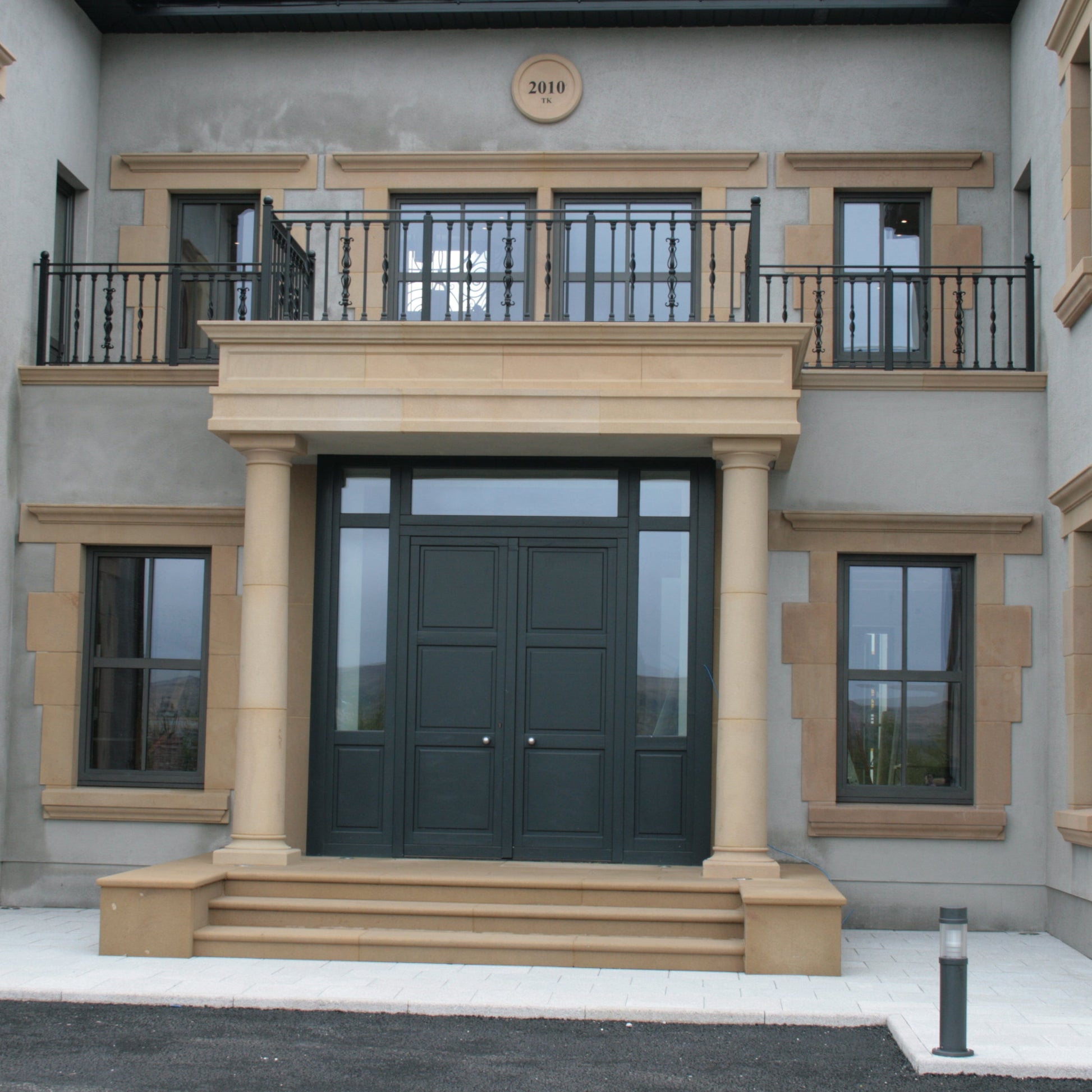 Stately house entrance with a large green door and decorative Sandstone Portico and steps.