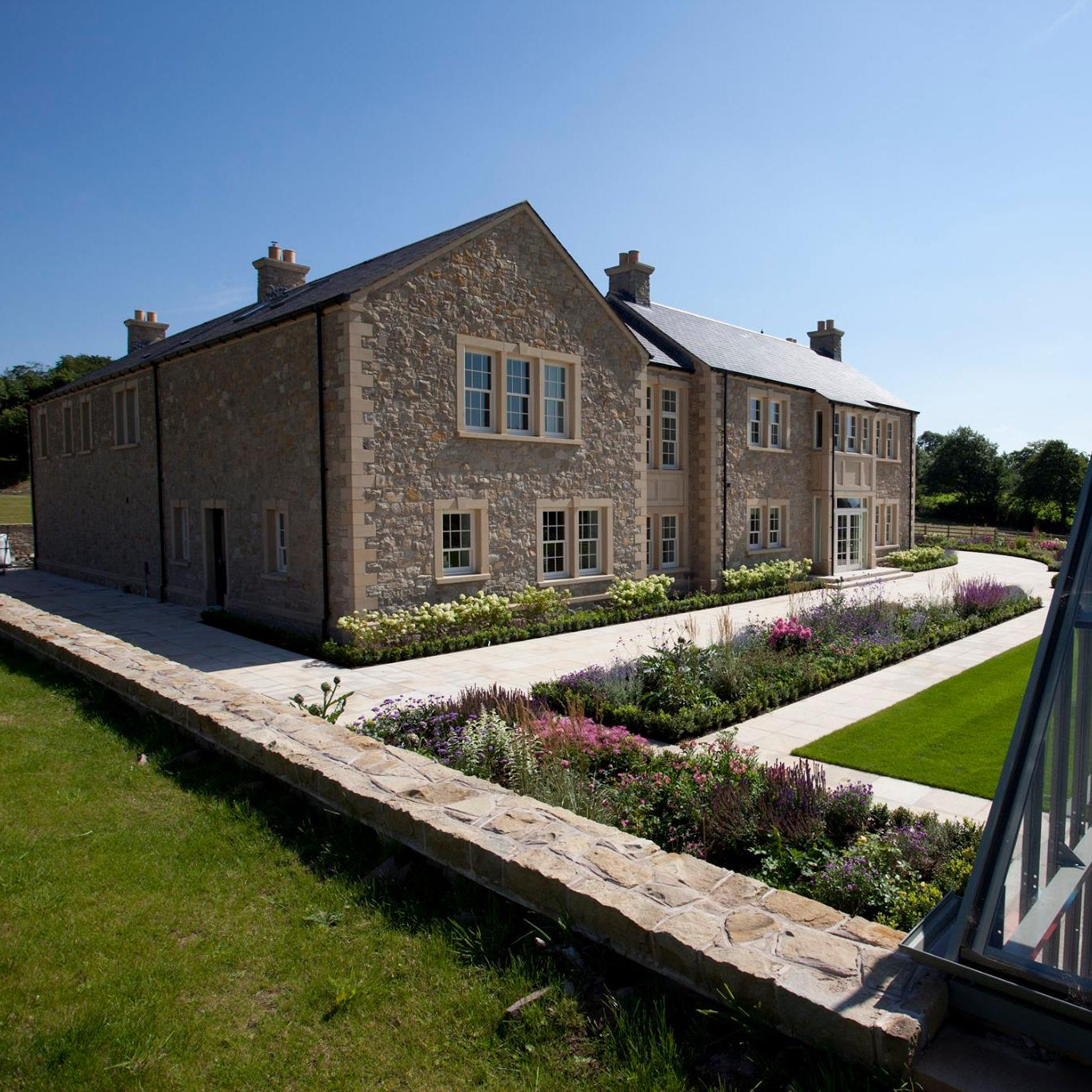 Large stone house with architectural sandstone quoins, window surrounds and string course. 