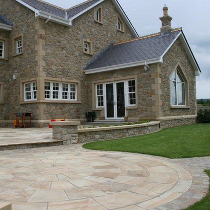 Back of stone house featuring architectural sandstone window surrounds, door surround, string course, wall capping, quoins and paving circle. 