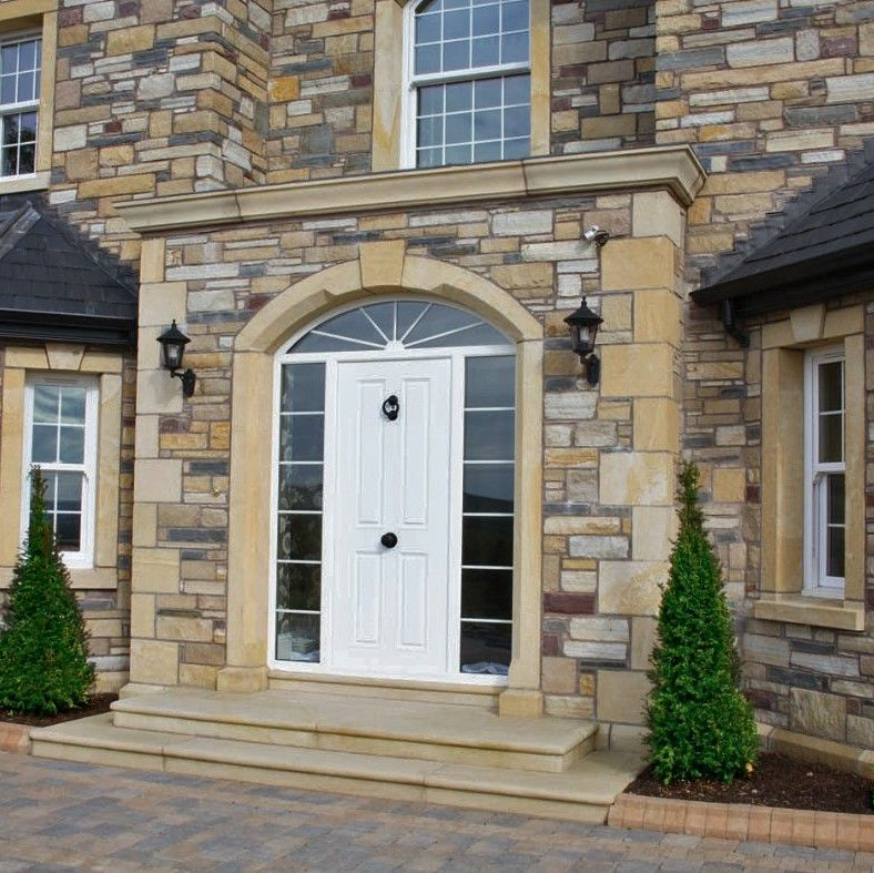 Stone house with architectural sandstone door & window surrounds, wall capping, steps and quoins. 