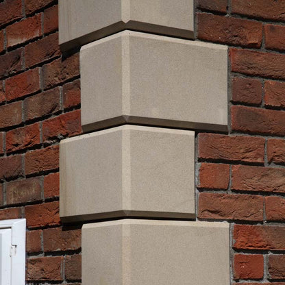 Close up of bespoke sandstone quoins on red brick building. 