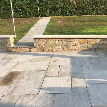 Low patio stone wall with flat sandstone wall capping leading to garden path.