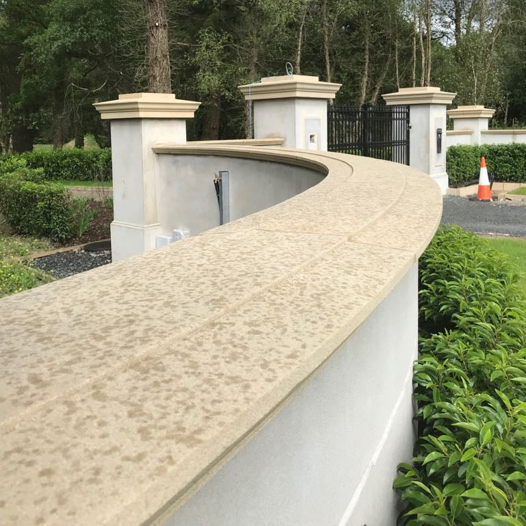 Curved Sandstone Wall Capping on an elegant boundary wall and black gate with trees and hedges in the background.  
