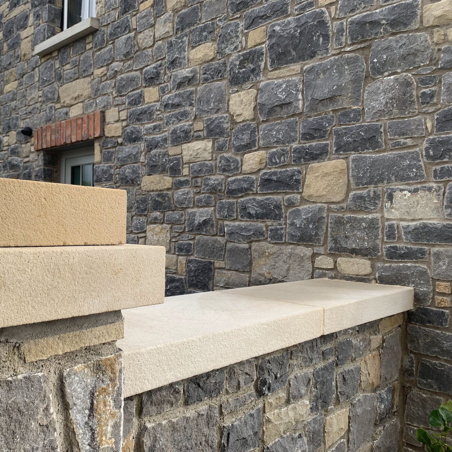 Garden wall joined on to natural stone house completed with bespoke Sandstone Wall & Pillar Capping. 