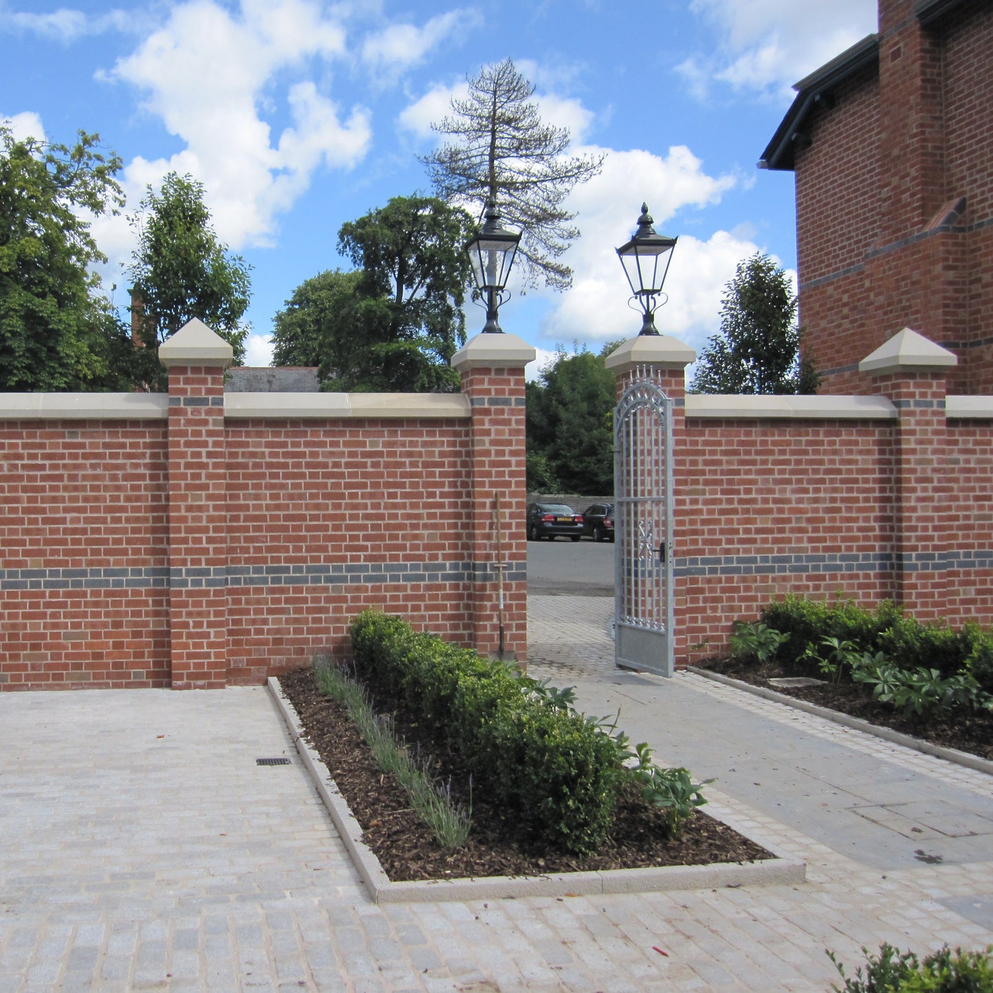 Brick wall with bespoke sandstone wall and pillar capping.