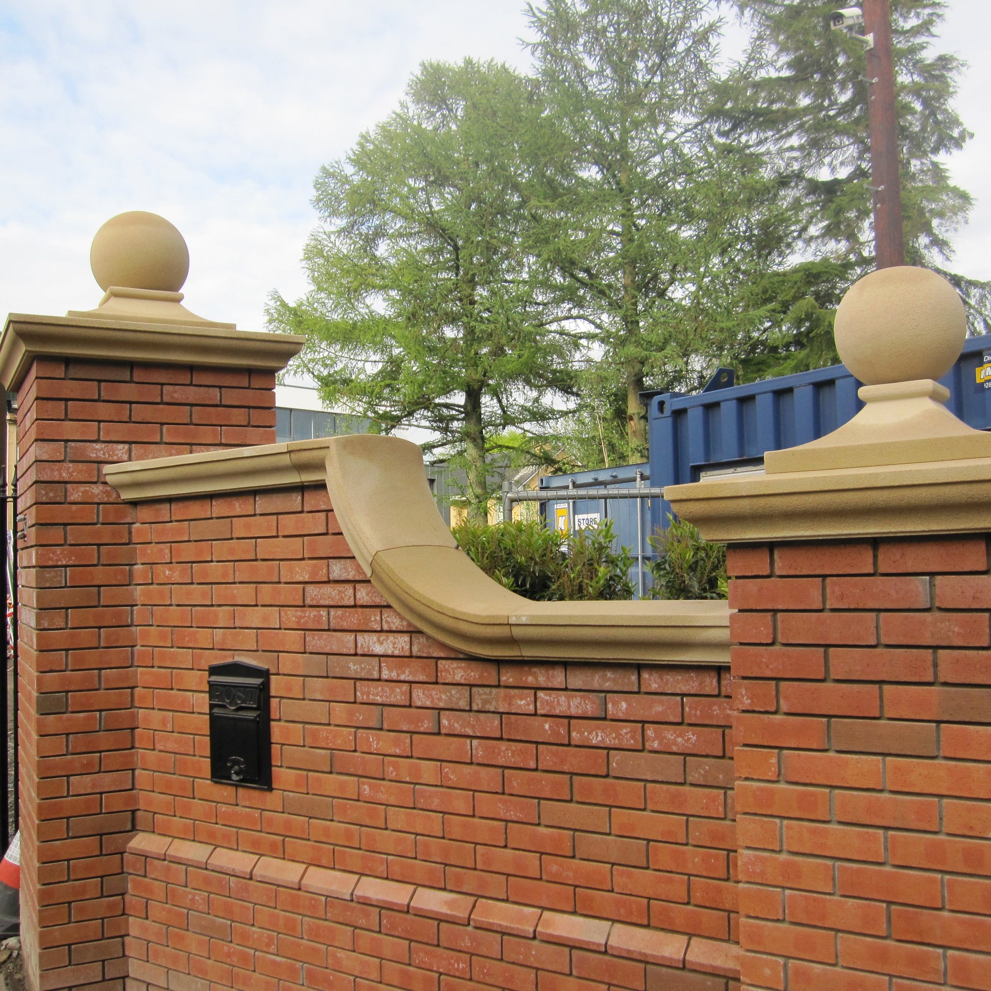 Brick wall with bespoke Sandstone wall and pillar capping with trees in the background