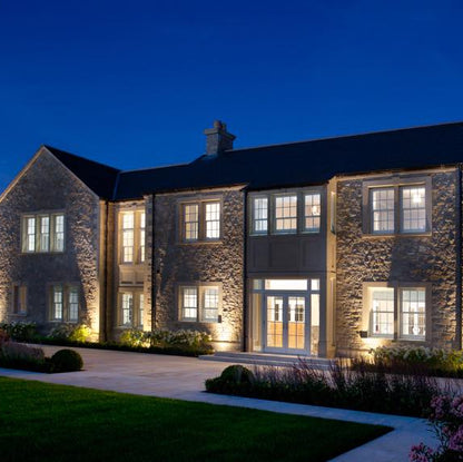 Large stone house photographed at night. House features architectural sandstone window and door surrounds. 