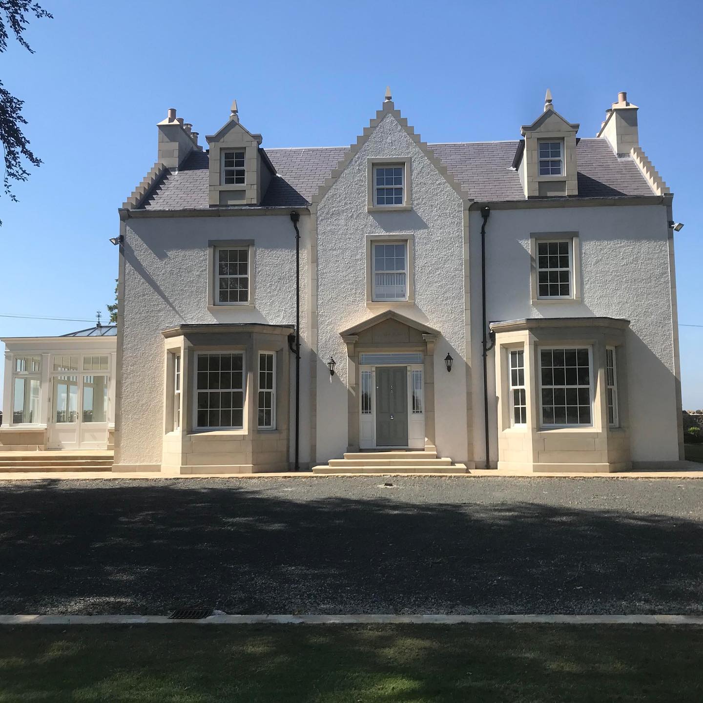 Large white house with beautiful sandstone window and door surrounds. 