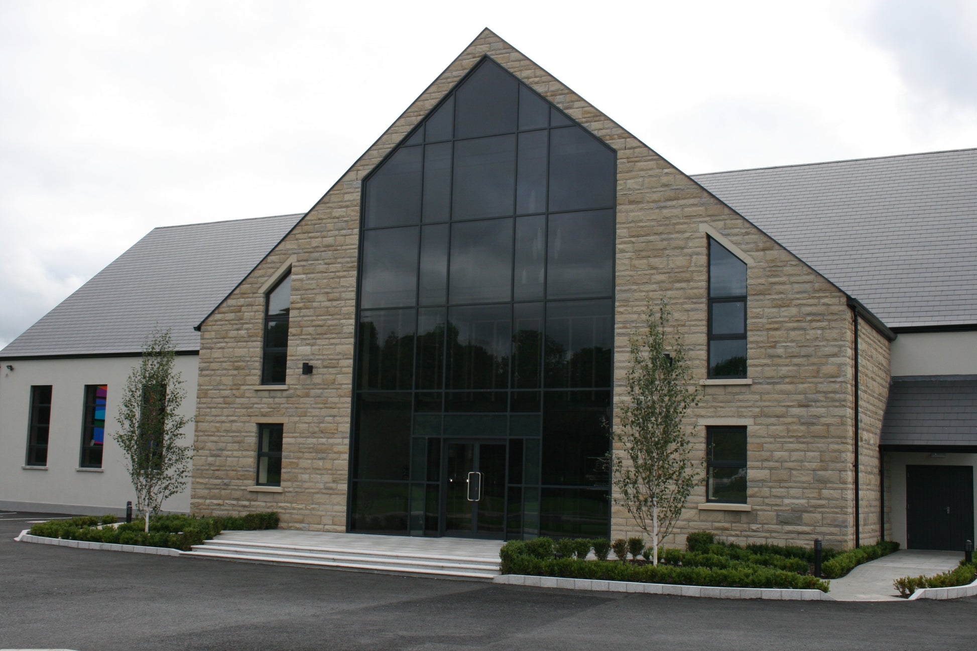 Modern building with large glass entrance and stone façade completed in Sawn Bed Sandstone Machined.