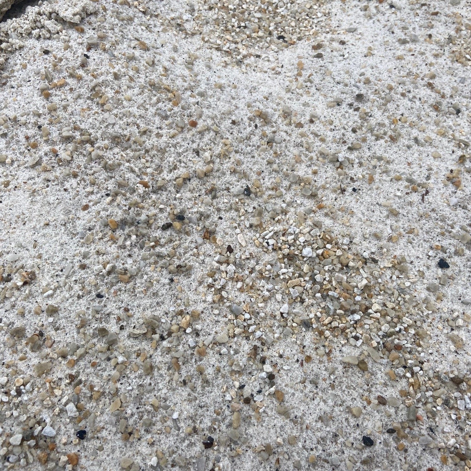 Close-up of a textured Self Binding Donegal Quartzite Gravel surface with small stones and dust. 
